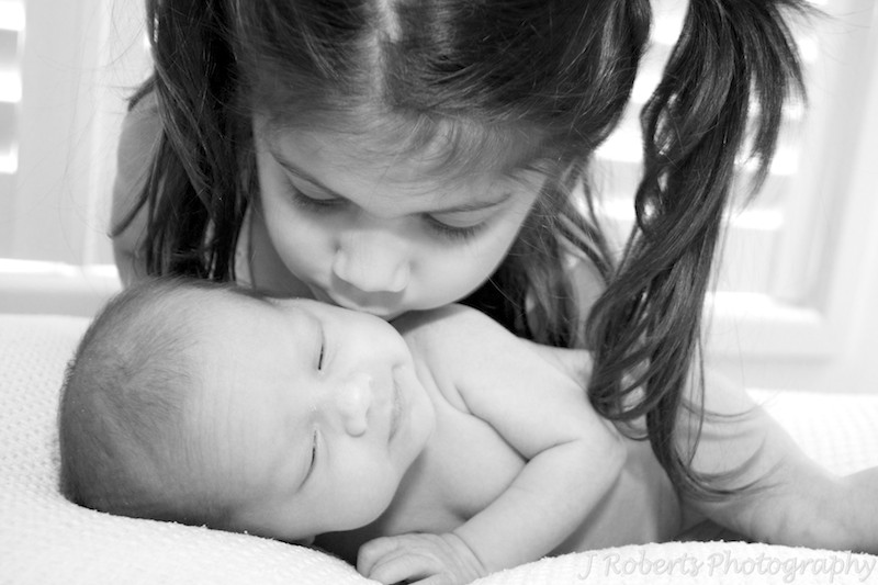 sister kissing newborn baby - newborn portrait photography sydney